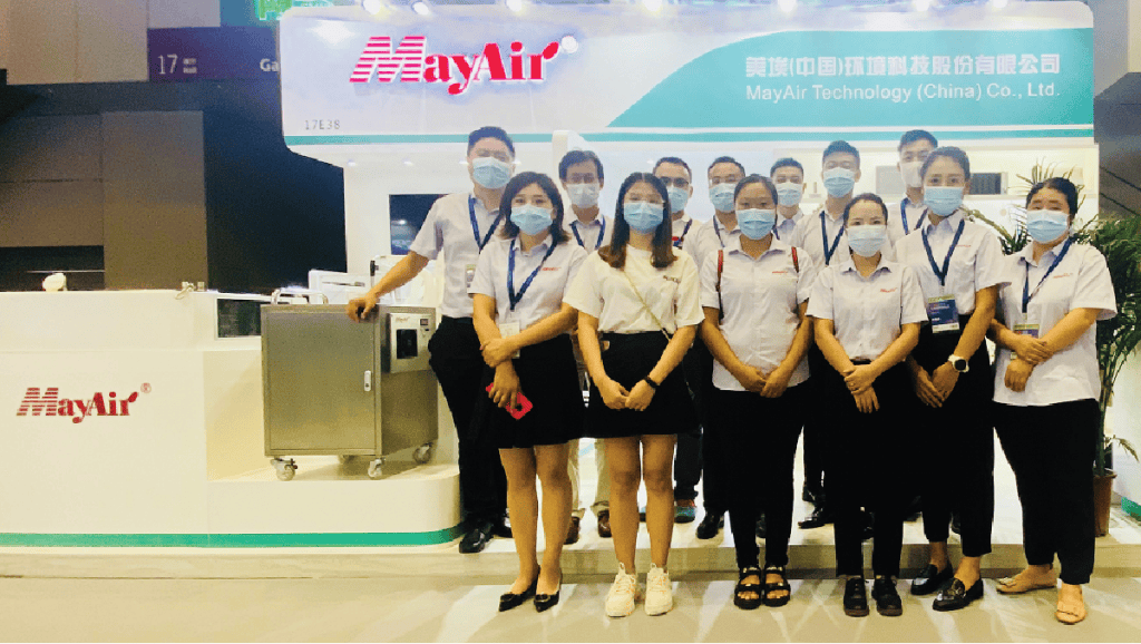 MayAir air purifiers and HVAC equipment displayed at a trade show booth with company staff, showcasing innovative air quality solutions and Chinese manufacturing expertise.