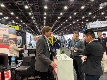 Modern trade show booth at MayAir US exhibition with professionals networking and discussing HVAC and air purification solutions.